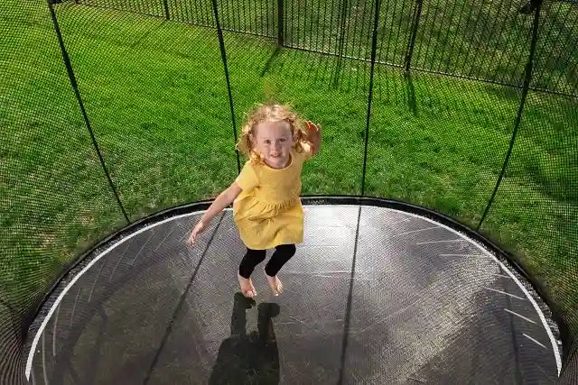 a young girl jumping on a trampoline