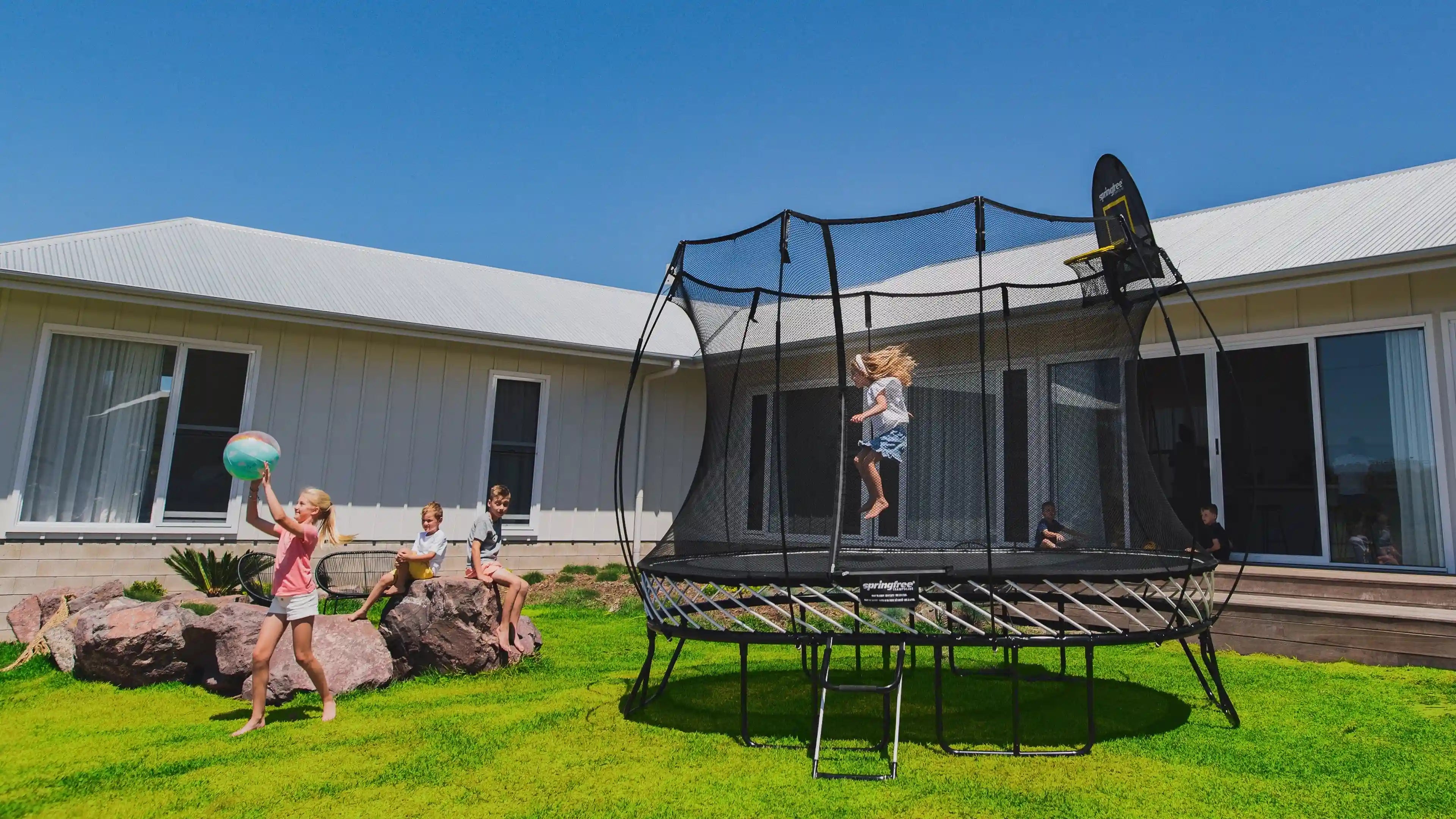 young girl jumping on the trampoline while other kids are watching her