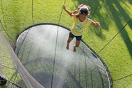 Load image into Gallery viewer, a young girl jumping on an outdoor trampoline