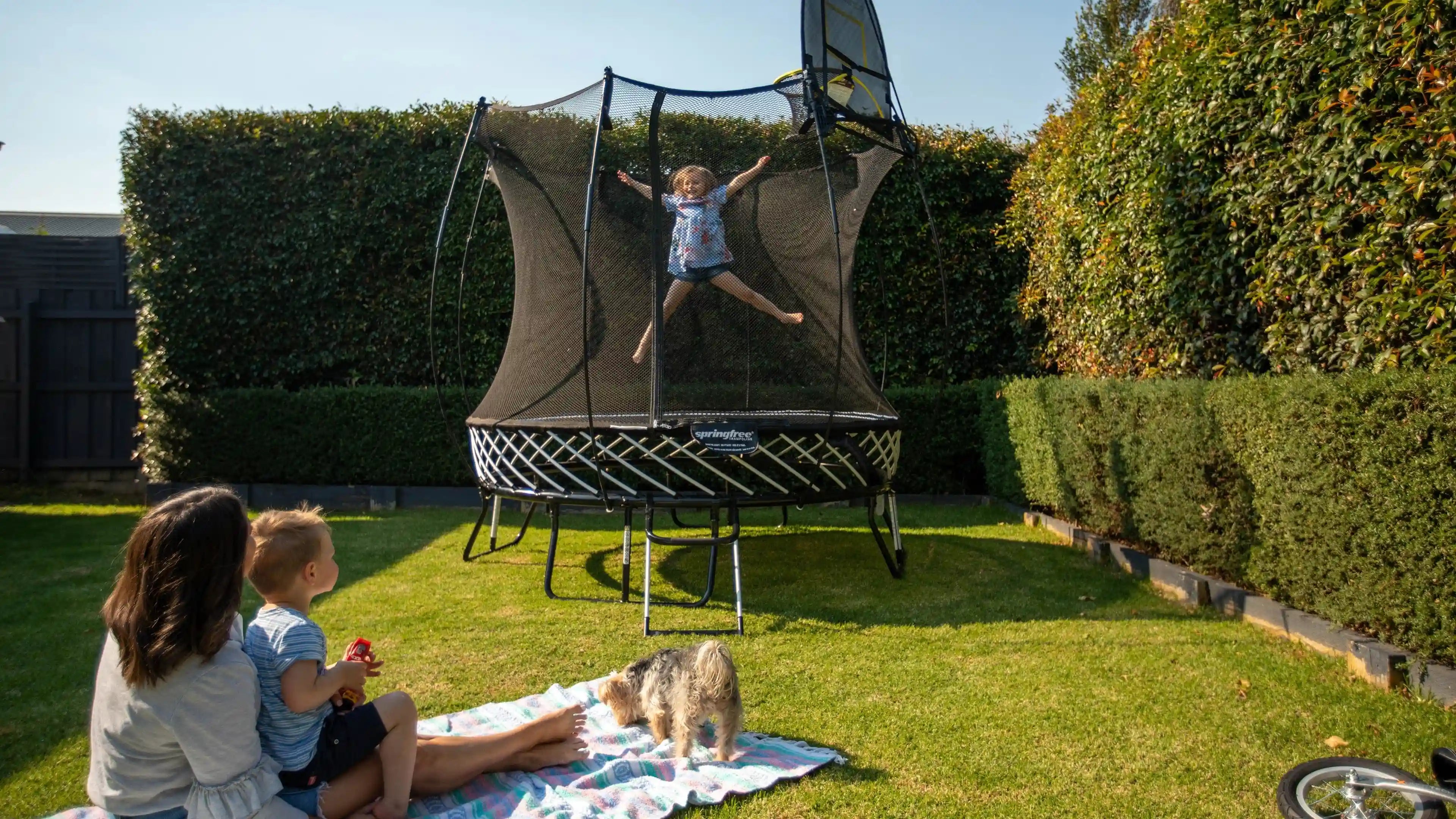 a girl jumping high on a trampoline while her family is watching