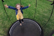 Load image into Gallery viewer, a young girl jumping on an outdoor trampoline