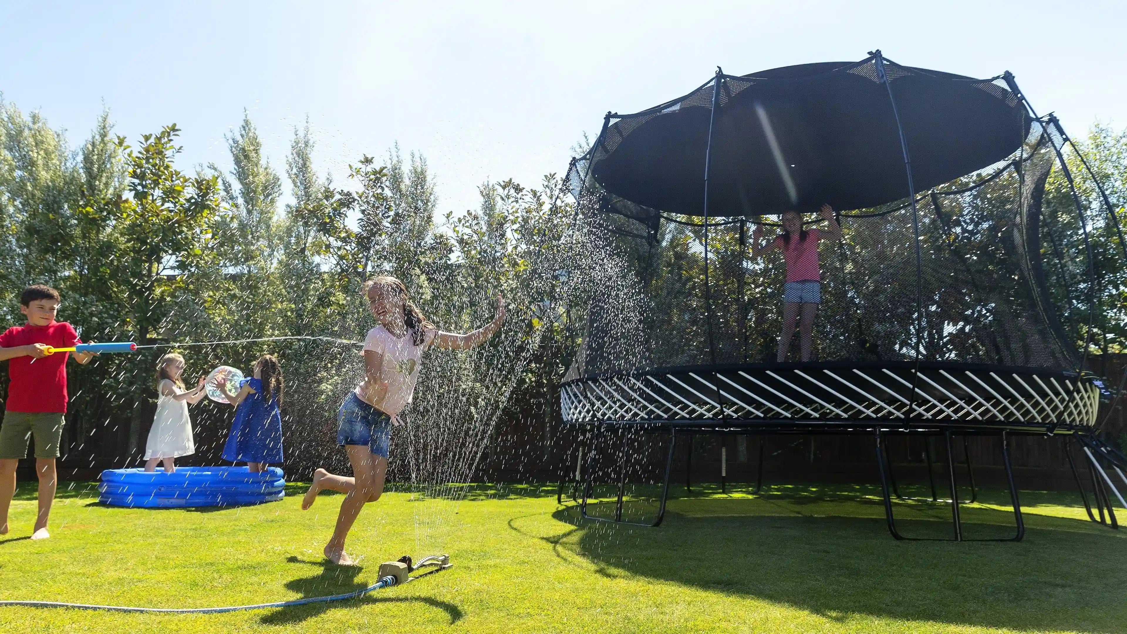 Kids playing around a trampoline with sun shade