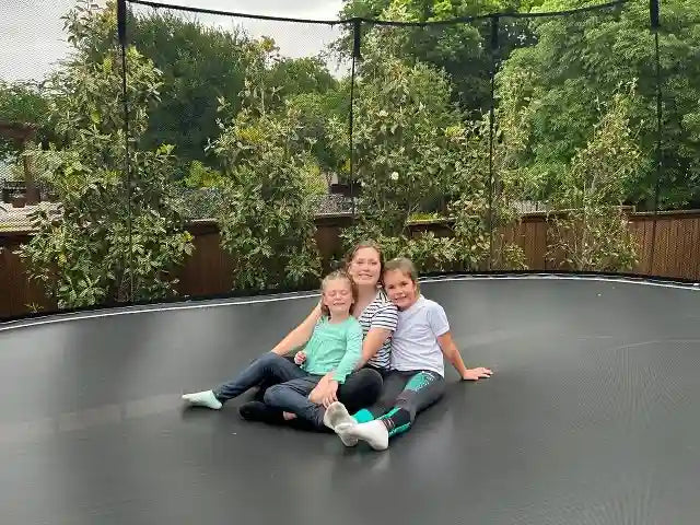 a mother and two kids sitting on a trampoline