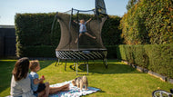 Load image into Gallery viewer, a girl jumping high on a trampoline while her family is watching

