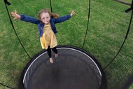 Load image into Gallery viewer, a young girl jumping on an outdoor trampoline
